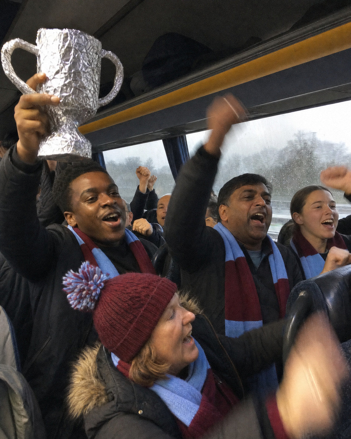 Fans on the coach home holding up a tin-foil trophy