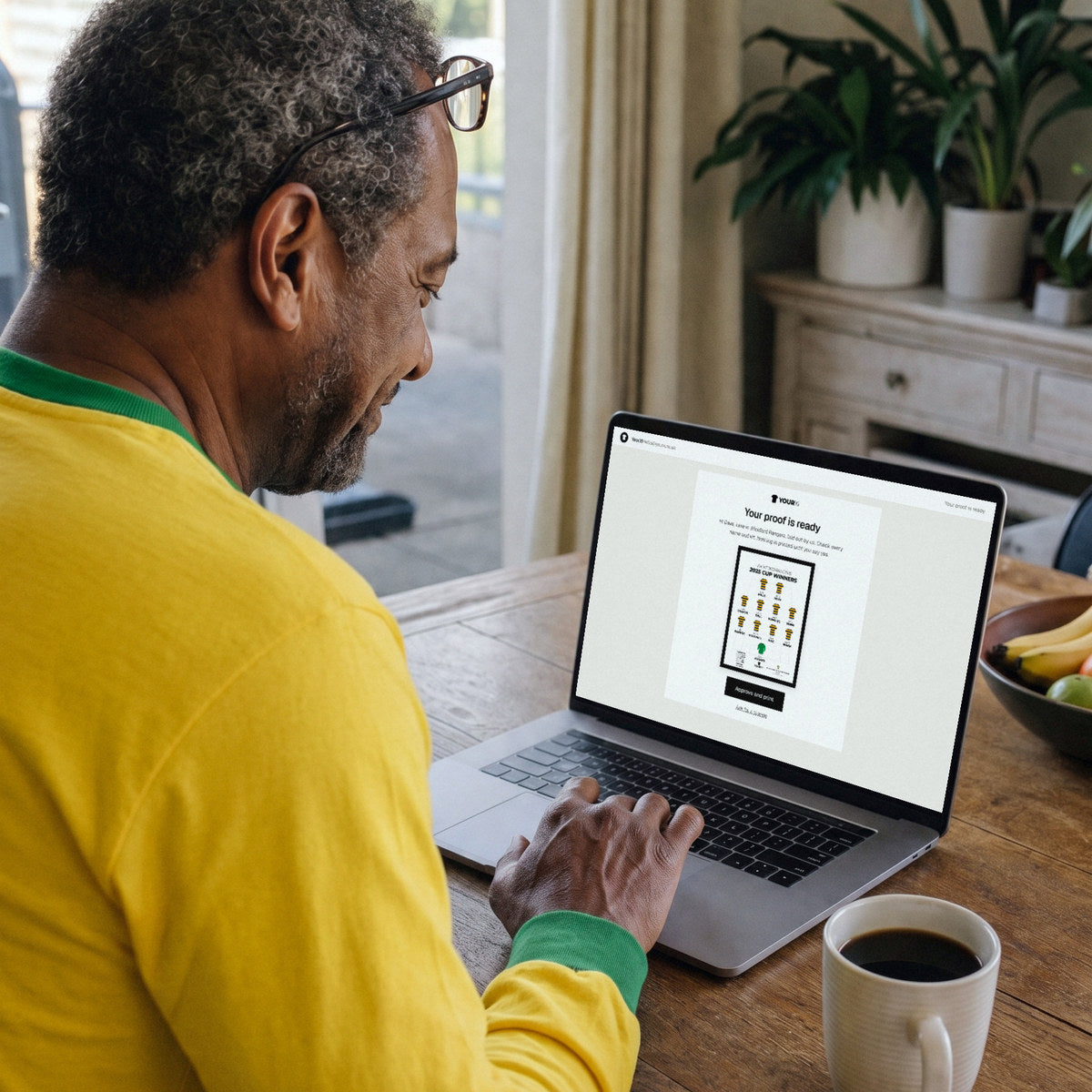 A fan in a retro yellow shirt approving his proof on a laptop